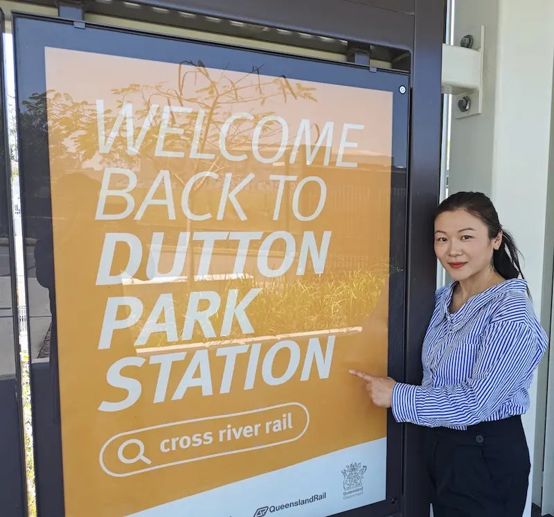 Dr Angel from Angel Chiropractic standing beside the Dutton Park Station sign, showing her dedication to supporting the local Dutton Park community.