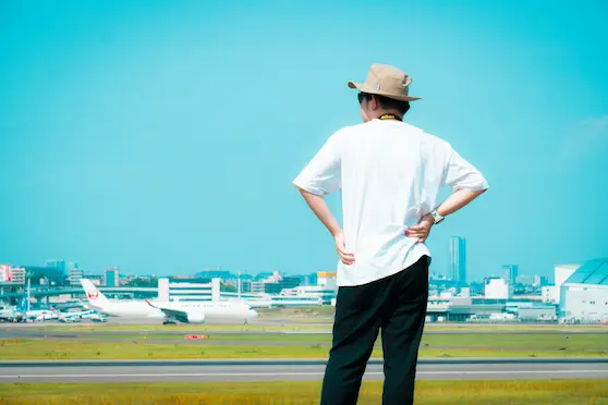 Man standing at an airport looking at airplanes, preparing for holiday travel with spine care tips from Angel Chiropractic.