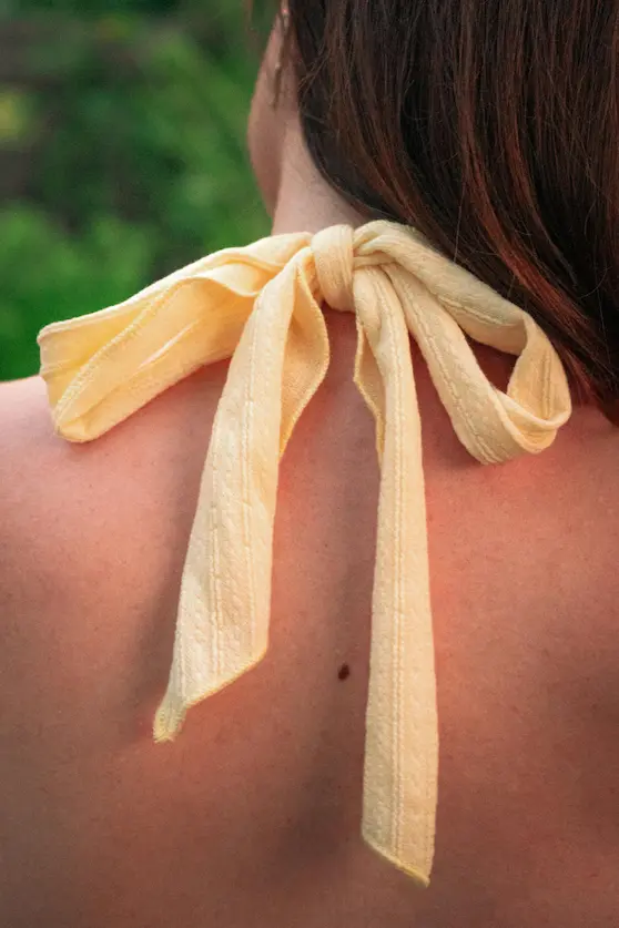 Woman with a knot tied at the back of her neck symbolising muscle tension treated at Angel Chiropractic Brisbane