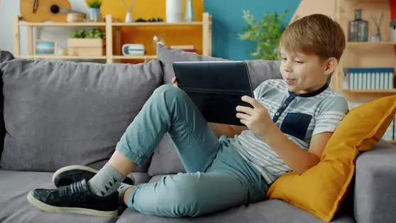 Children’s posture: boy using a tablet with poor posture on a couch | Angel ChiropracticTitle: Poor Posture While Using a Tablet |